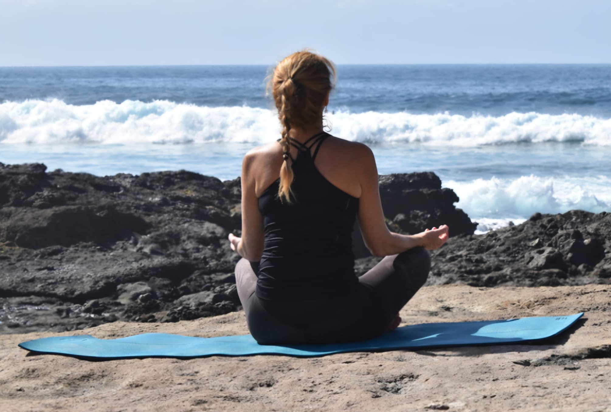 Woman practising yoga by the sea in Tenerife