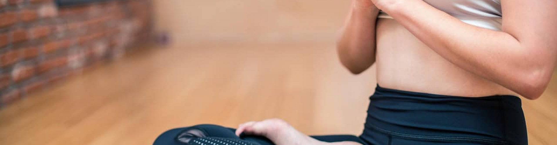 Woman meditating in a yoga pose indoors for relaxation and mindfulness.