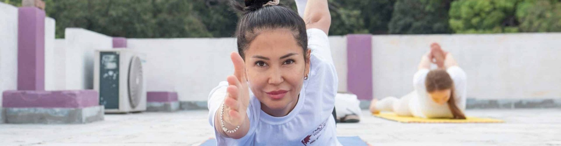 Woman practicing yoga outdoors on a rooftop with scenic greenery in Tenerife.