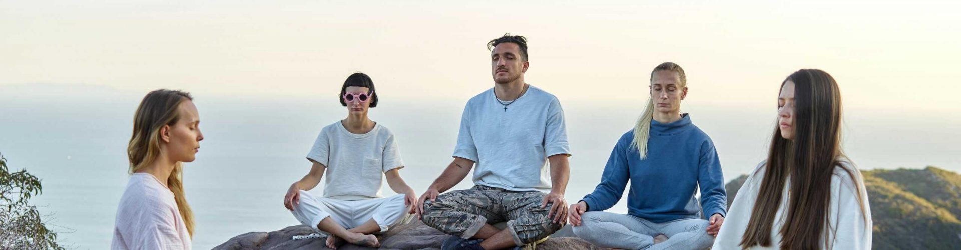 Mindfulness meditation session on a rocky hilltop overlooking the sea.